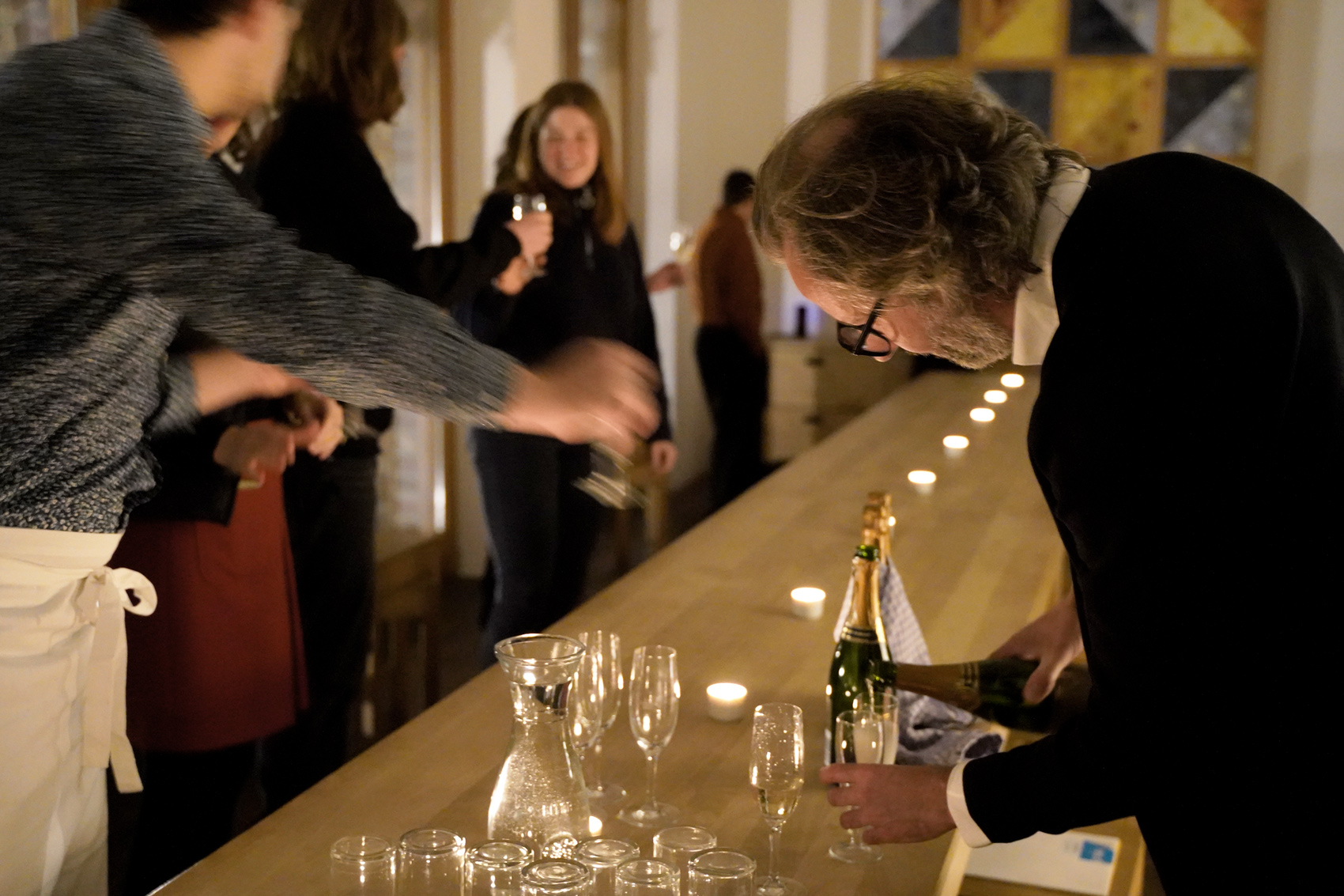 Eine festliche Tafel mit Teelichtern und Ingo Plato verteilt Sekt.