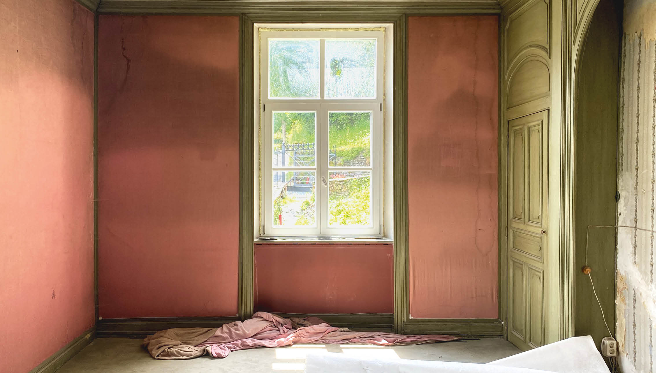 Blick von innen auf ein Fenster umrandet von lachsfarbenen Wänden