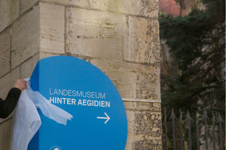 Handwerker bei der Montage eines runden Orientierungsschildes in Blau