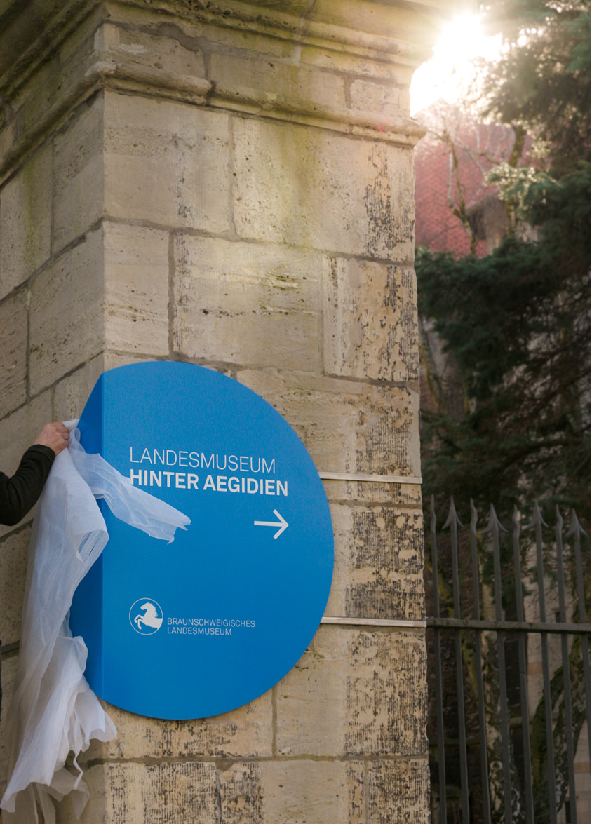 Handwerker bei der Montage eines runden Orientierungsschildes in Blau
