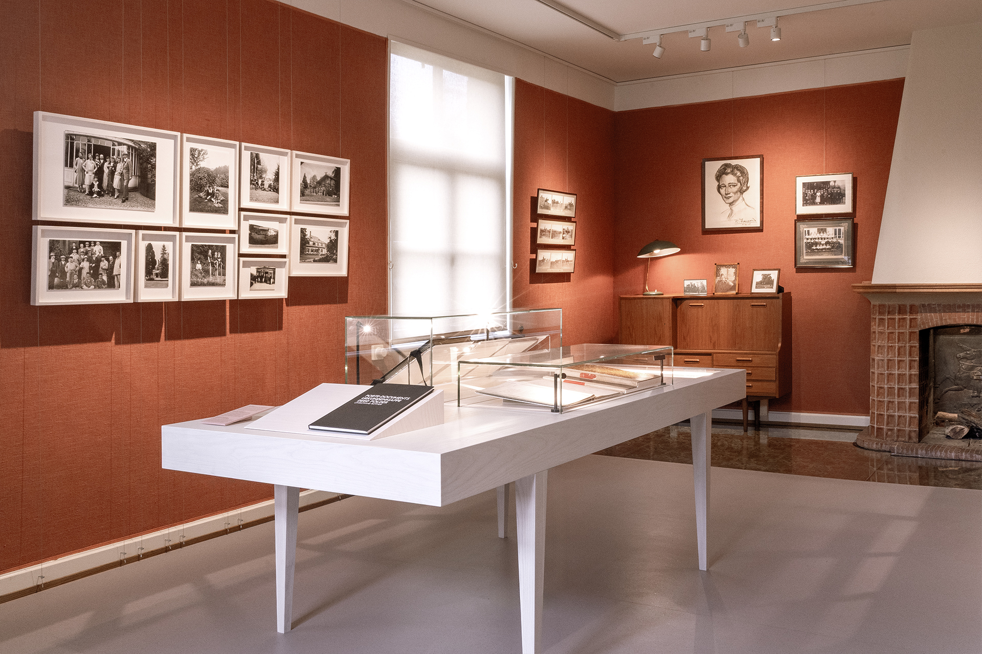 Ausstellungsraum mit Vitrinen und abgehängten Fotografien