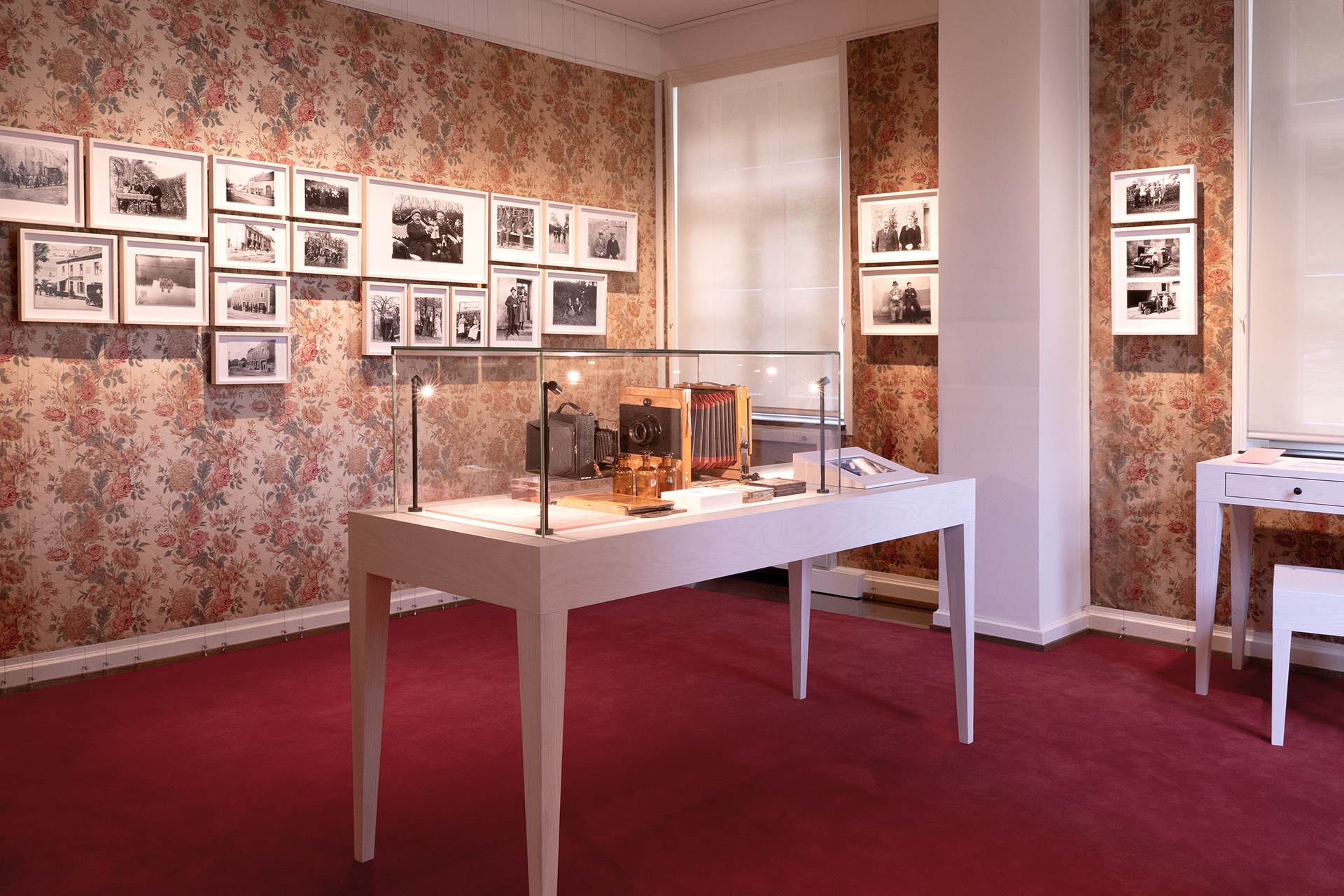Ausstellungsraum mit Vitrinen und abgehängten Fotografien